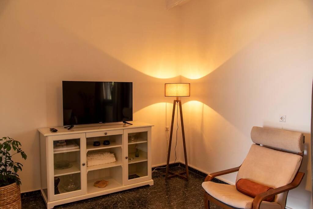 salon z telewizorem, krzesłem i lampką w obiekcie Julia's House w mieście Palekastron