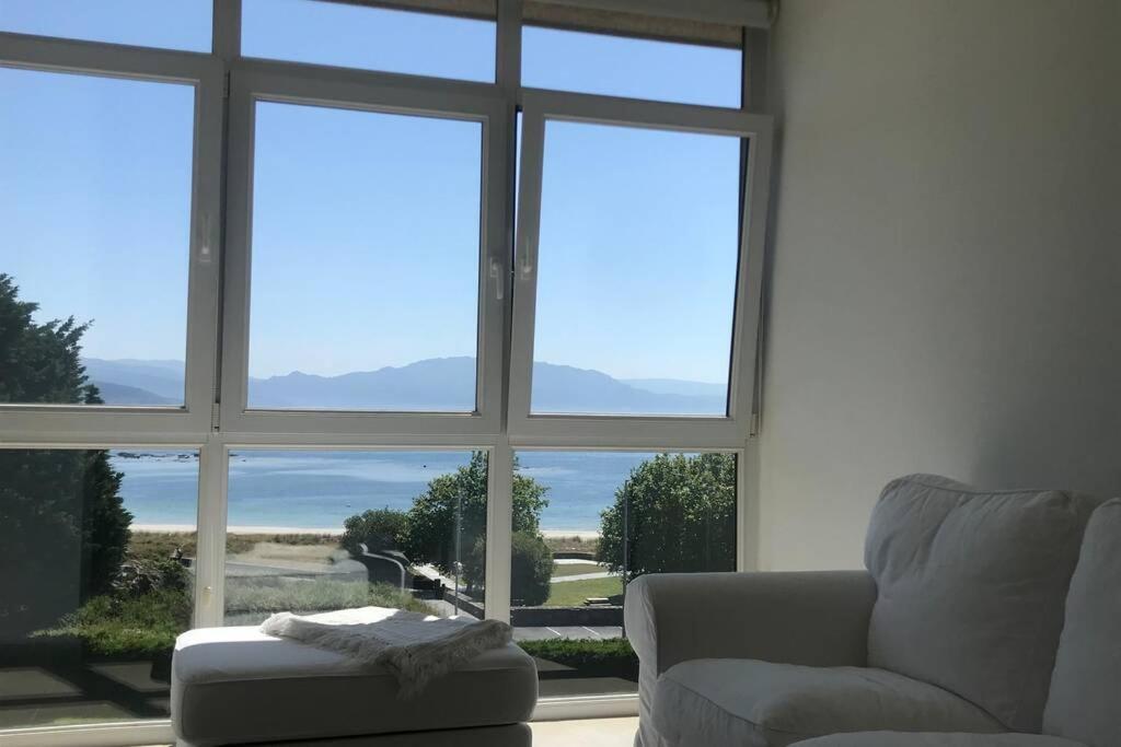 a living room with a couch and a large window at Apartamento primera línea de playa in Finisterre