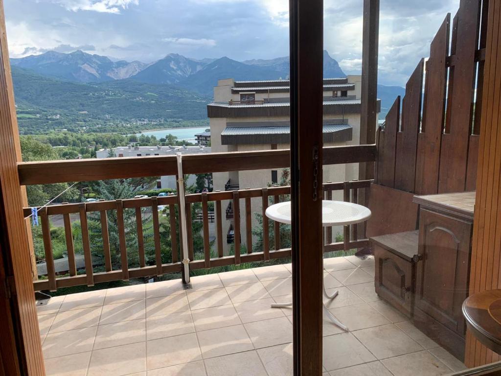 a balcony with a view of a building and mountains at Studio Embrun plan d eau de 2 à 4 personnes situé 3 chemin de chadenas in Embrun