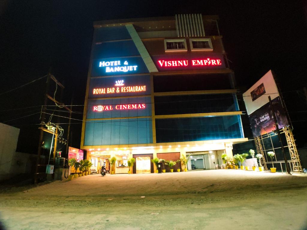 a building with neon signs on it at night at Hotel Vishnu Empire in Rewa