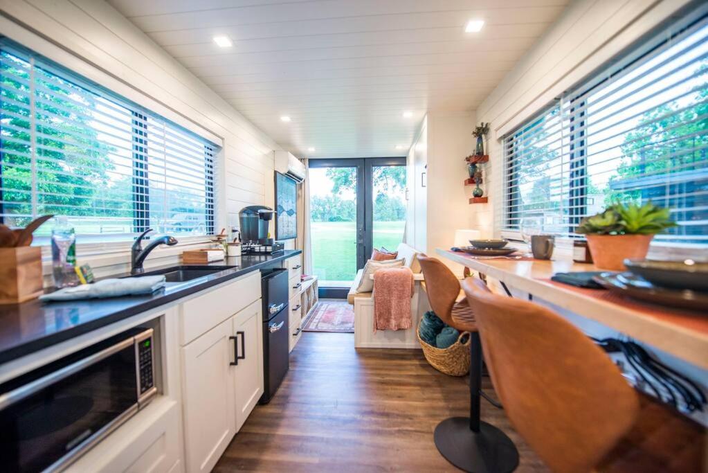 a kitchen with a sink and a counter with chairs at NEW The Brazos-Tiny Home 12 Min to downtown in Bellmead