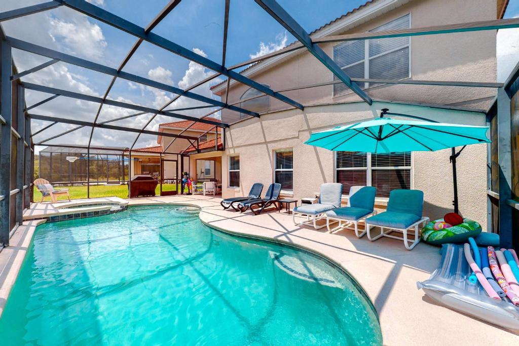 a swimming pool with chairs and an umbrella at Paradise Villa in Davenport