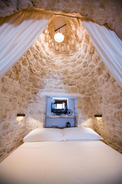 sypialnia z łóżkiem w kamiennej ścianie w obiekcie Il Trullo della Rondinina w Alberobello