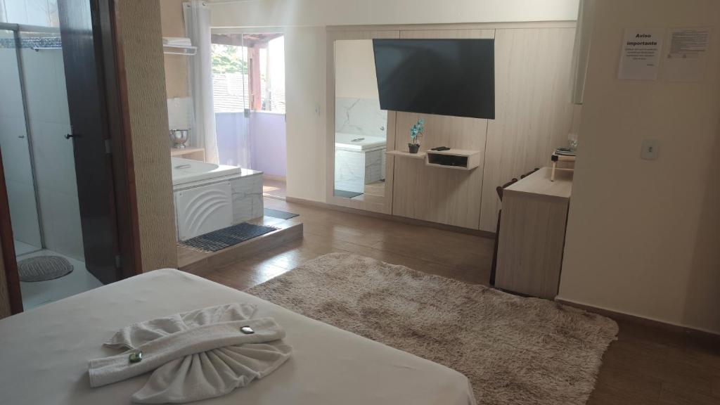 a room with a bed and a tv and a bathroom at Pousada Antares in São Thomé das Letras
