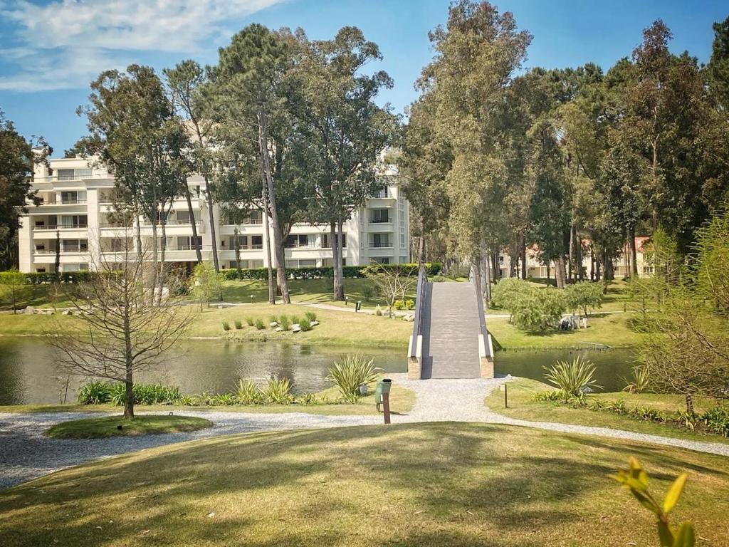 a park with a bridge over a lake and a building at Green Park 2 Ambientes con Balcón Vista Bosque o Laguna con Parrillero in Punta del Este