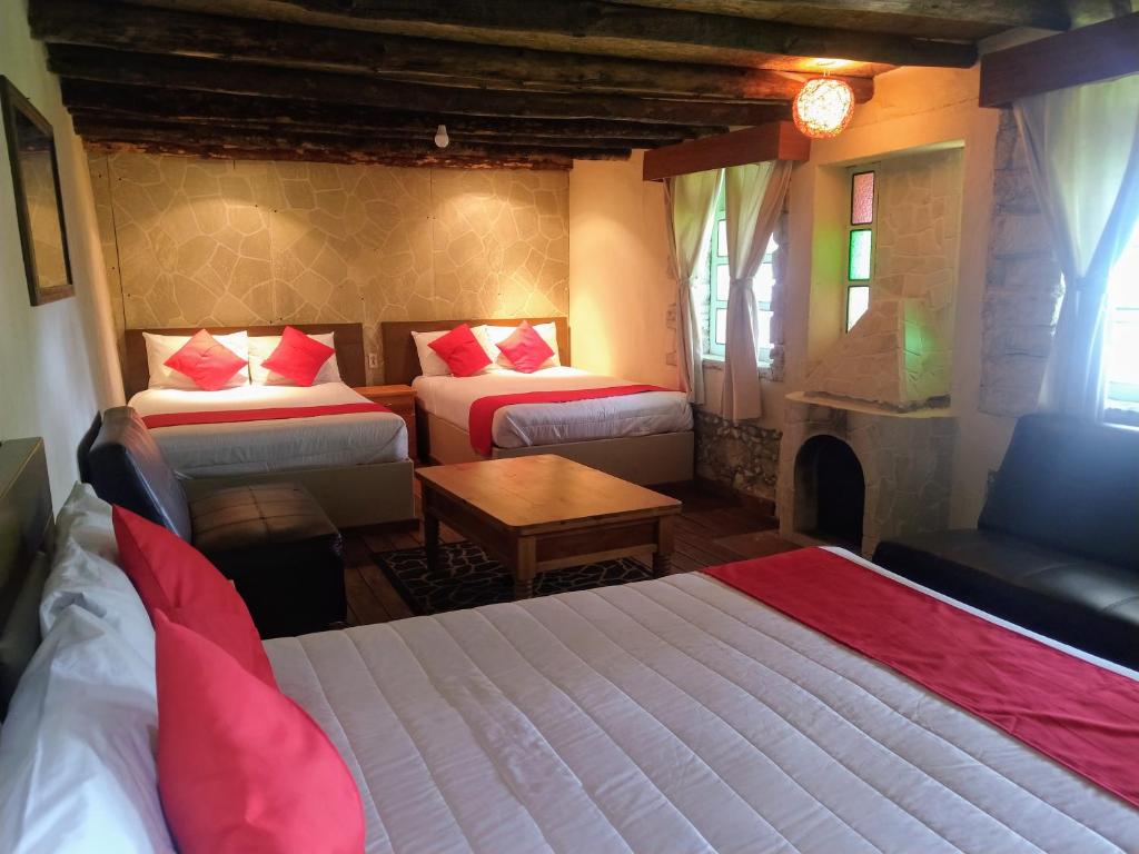 Habitación de hotel con 2 camas y mesa en Hotel Rincon Del Real, en Mineral del Monte