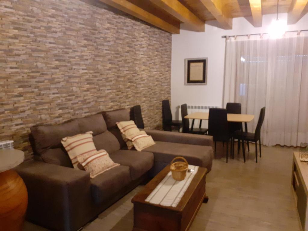 sala de estar con sofá y pared de ladrillo en Apartamentos CASA RURAL EL VENTANICO, en Olocau del Rey