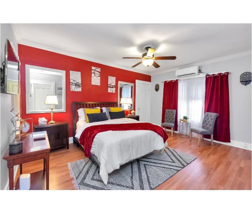 a bedroom with red walls and a bed and a ceiling fan at Cozy Downtown Studio by Toyota Center in Houston