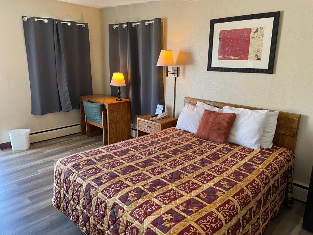 Habitación de hotel con cama y escritorio con lámpara. en Rivers Inn, en Fort Madison