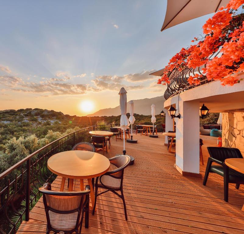a balcony with tables and chairs and the sunset at Hill House Adult Only in Kaş