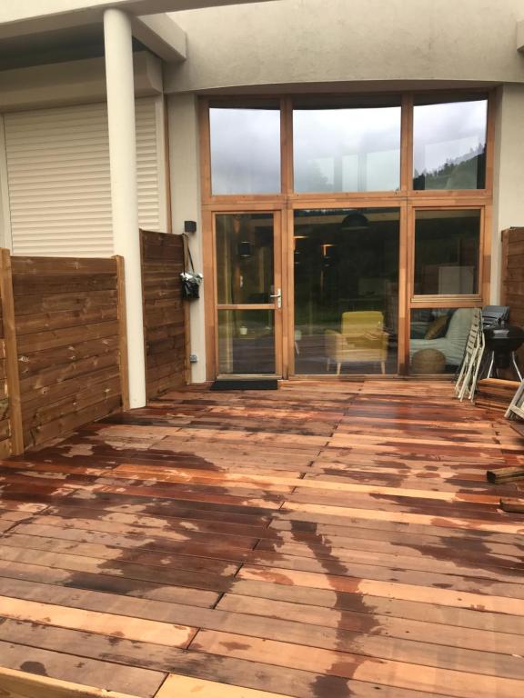 une terrasse vide avec des portes coulissantes en verre sur une maison dans l'établissement Bel appartement neuf équipé au pied des pistes du HONHECK, à La Bresse