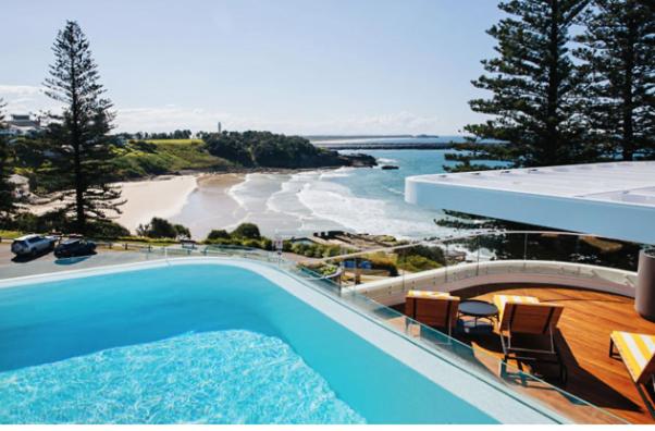 a swimming pool with a view of a beach and the ocean at The Surf Yamba in Yamba