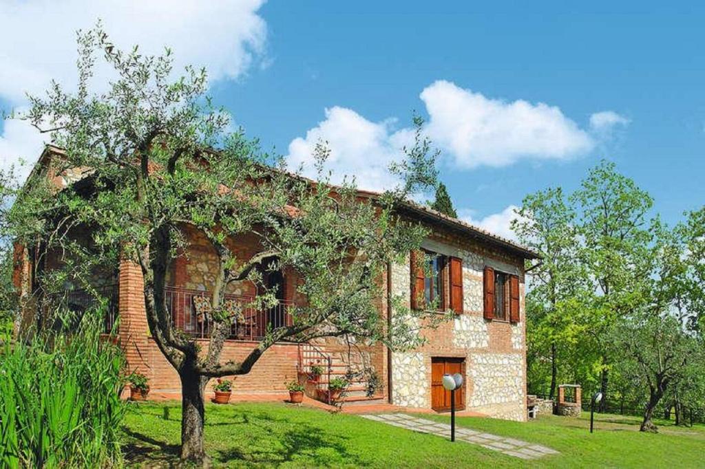 una casa di mattoni con un albero di fronte di Villa la Stellina a San Gimignano