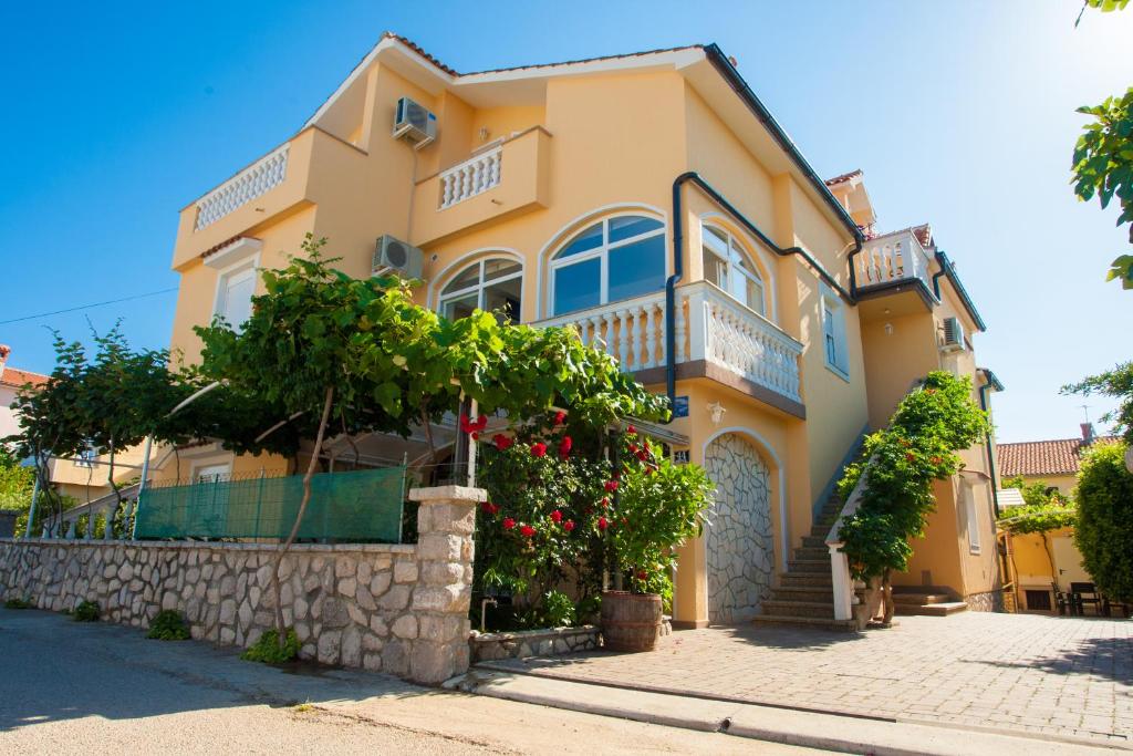 a yellow house with trees and flowers in front of it at Pansion Tina in Šilo