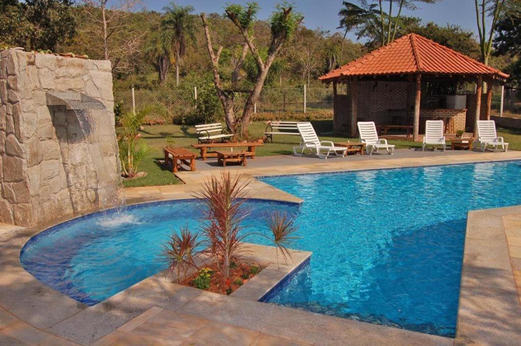 a swimming pool with chairs and a gazebo at Pousada Di Luna in Bonito