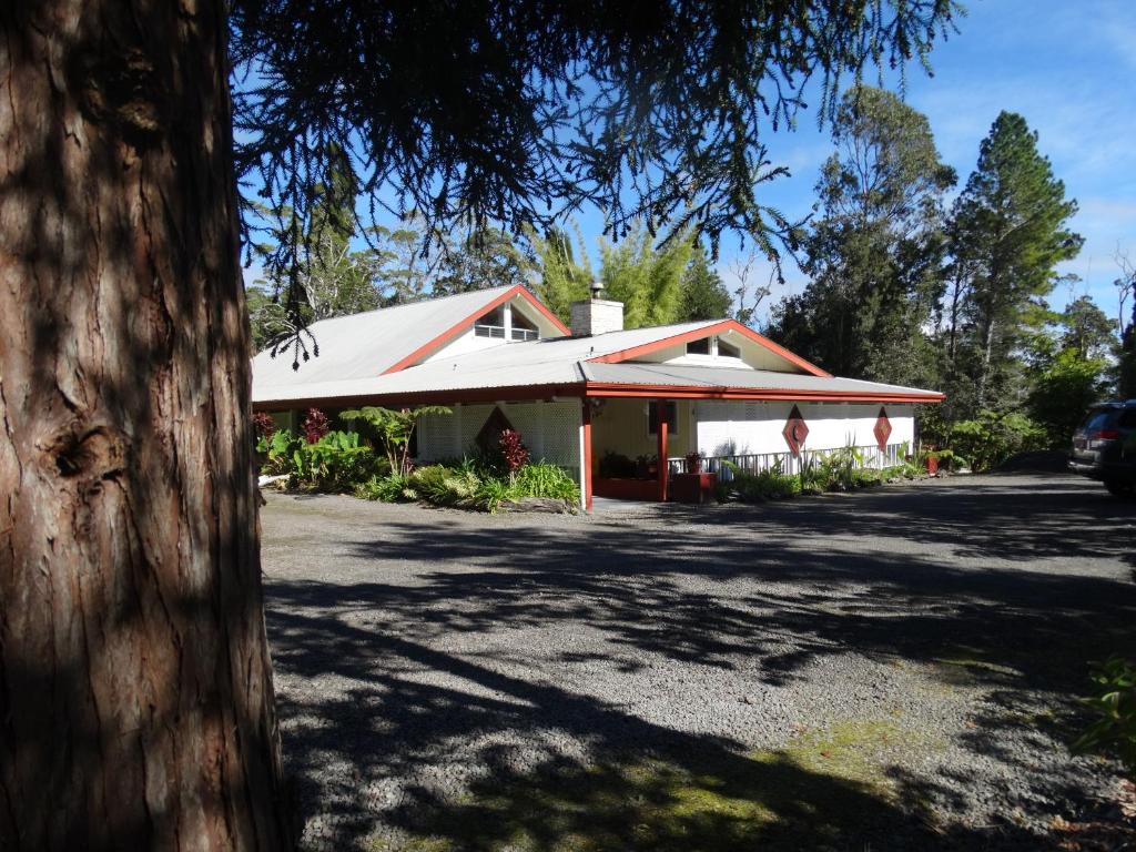 una casa con un techo blanco y un árbol en Lokahi Lodge en Volcano