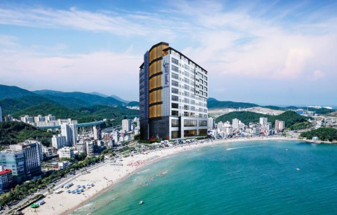 a building on a beach next to the ocean at Songjeong Blue Castle Hotel in Busan