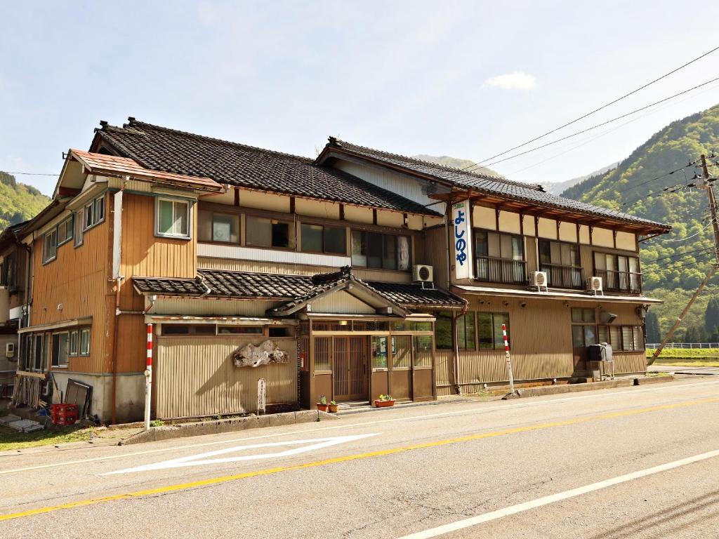 a building on the side of a street with a mountain at 富山県 よしのや旅館 in Nanto