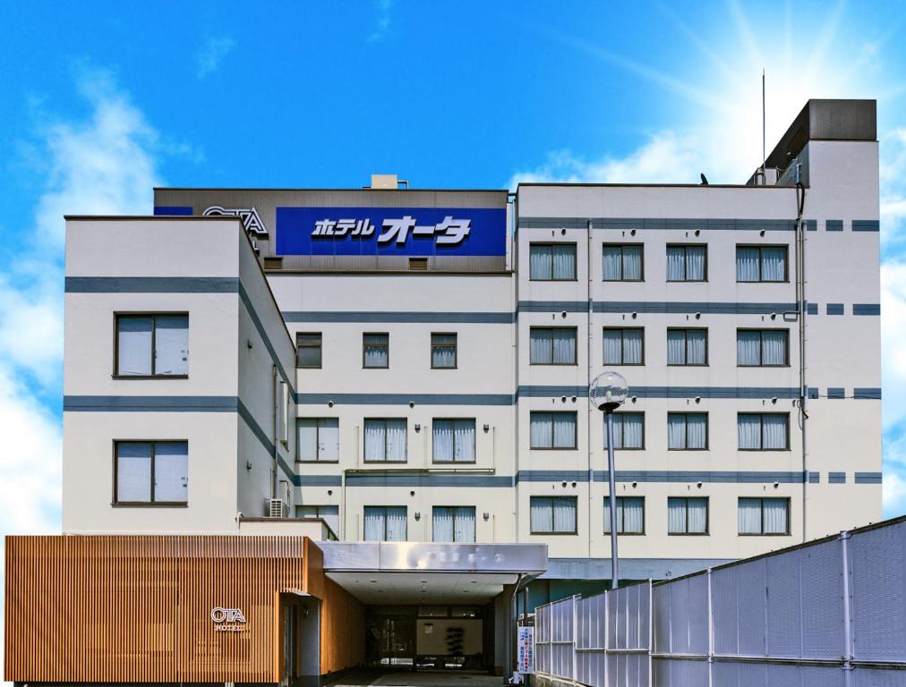 a white building with a blue sign on it at Hotel Ohta in Ōzu