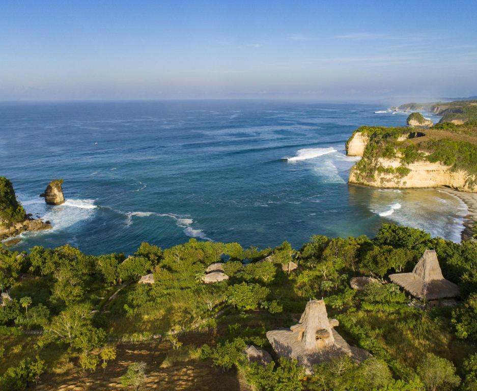 an aerial view of the ocean with rocks and trees at Ngalung Kalla Retreat in Waikabubak