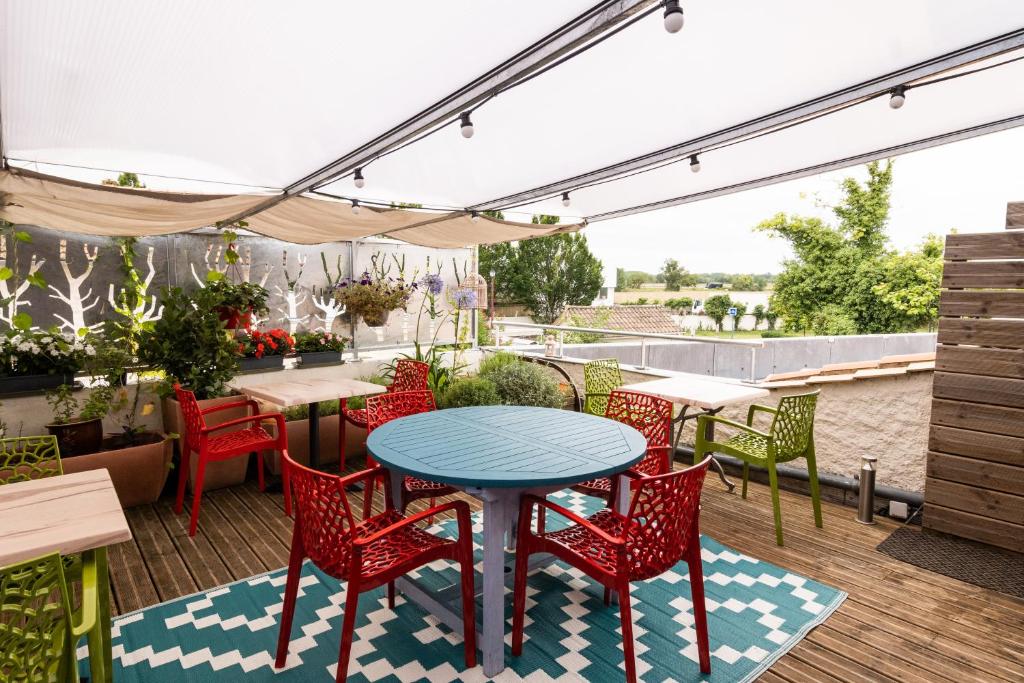 a patio area with tables, chairs, and tables with umbrellas at Hôtel de la Gare in Latresne