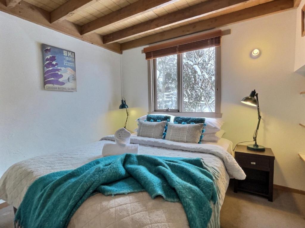 a bedroom with a bed with a blue blanket on it at Merrigang Chalet, Dinner Plain in Dinner Plain