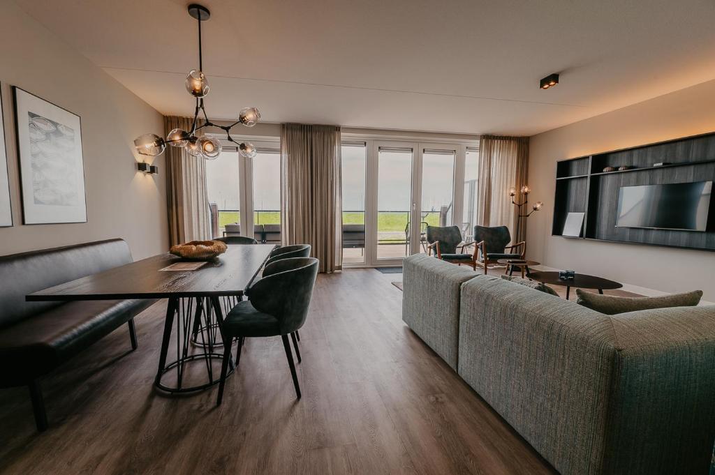 a living room with a couch and a dining room table at Residence Oude Haven luxe appartementen met sauna in Colijnsplaat