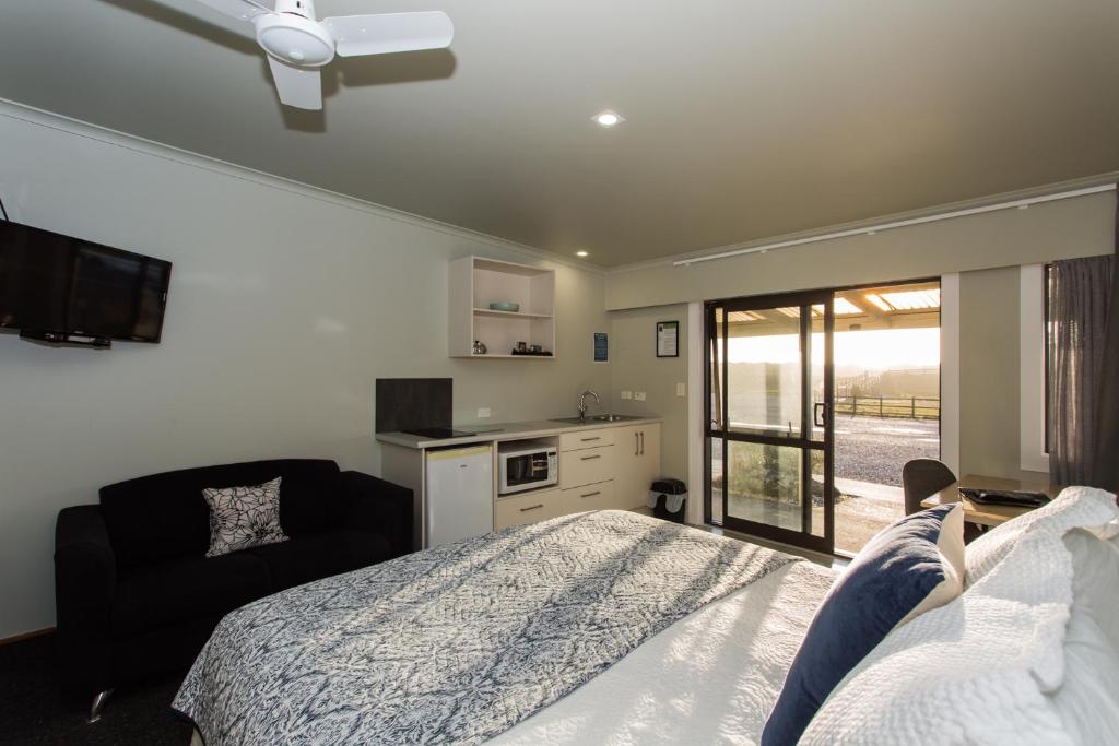 a bedroom with a bed and a chair and a kitchen at Haast Beach Motel in Haast