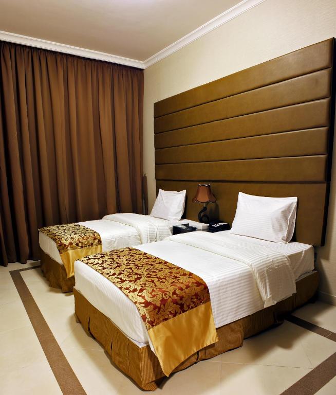 a hotel room with two beds and a headboard at Paragon Hotel Apartments in Abu Dhabi