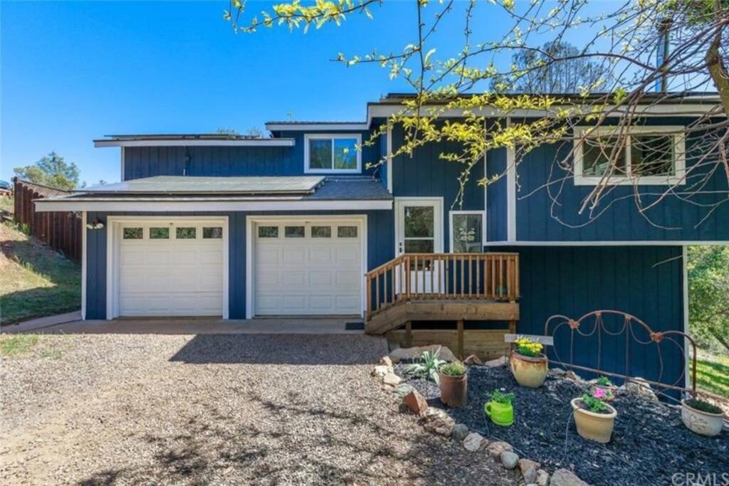 a blue house with two garage doors and a porch at Yosemite Oasis in Mariposa