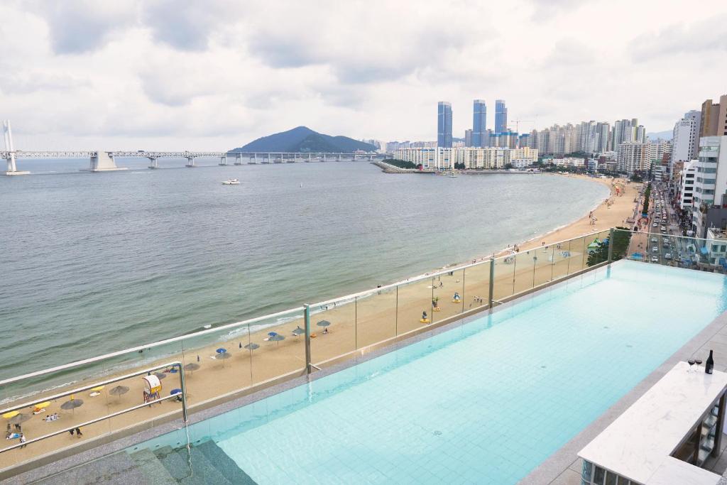 a swimming pool next to a beach and the ocean at Hotel Aqua Palace in Busan