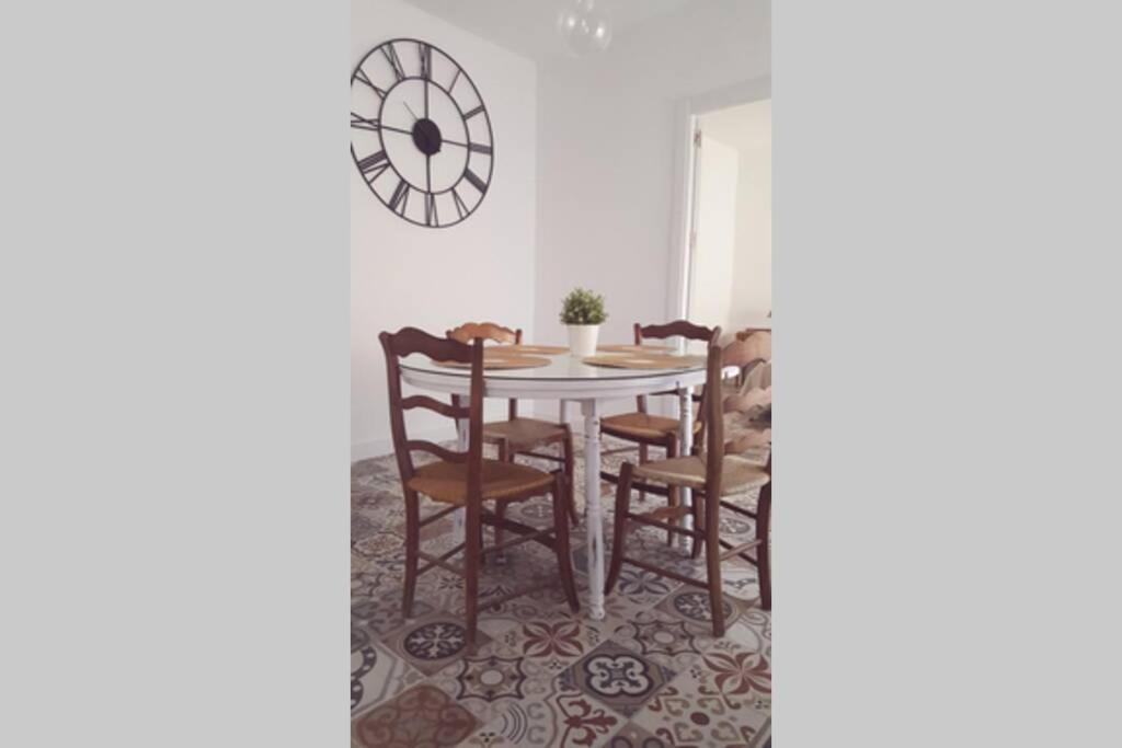 comedor con mesa, sillas y reloj en Apartamento con encanto, entrada privada, en Valdepeñas