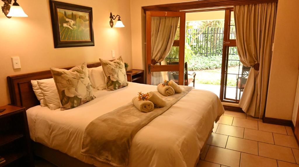 a bedroom with a bed with two stuffed animals on it at LUXURY EN-SUITE KING ROOM @ 4 STAR GUEST HOUSE in Middelburg