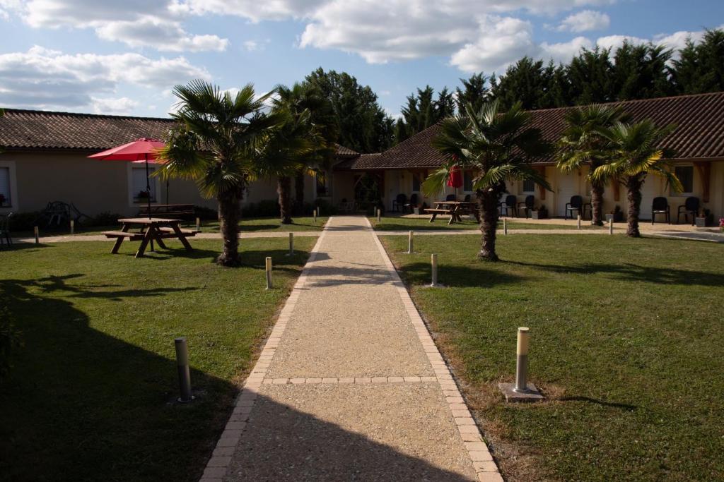 einen Weg in einem Park mit Palmen und Picknicktischen in der Unterkunft Rev'hotel in Ribérac