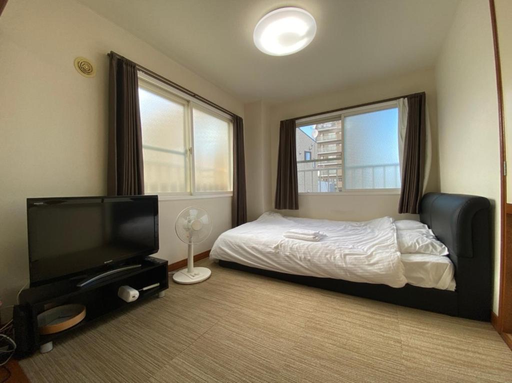 a bedroom with a bed and a flat screen tv at カプリス豊平公園305 in Sapporo