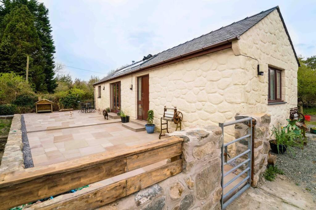 ein Haus mit einer Holzterrasse und einem Gebäude in der Unterkunft Bwthyn Bach Cozy country retreat in Criccieth