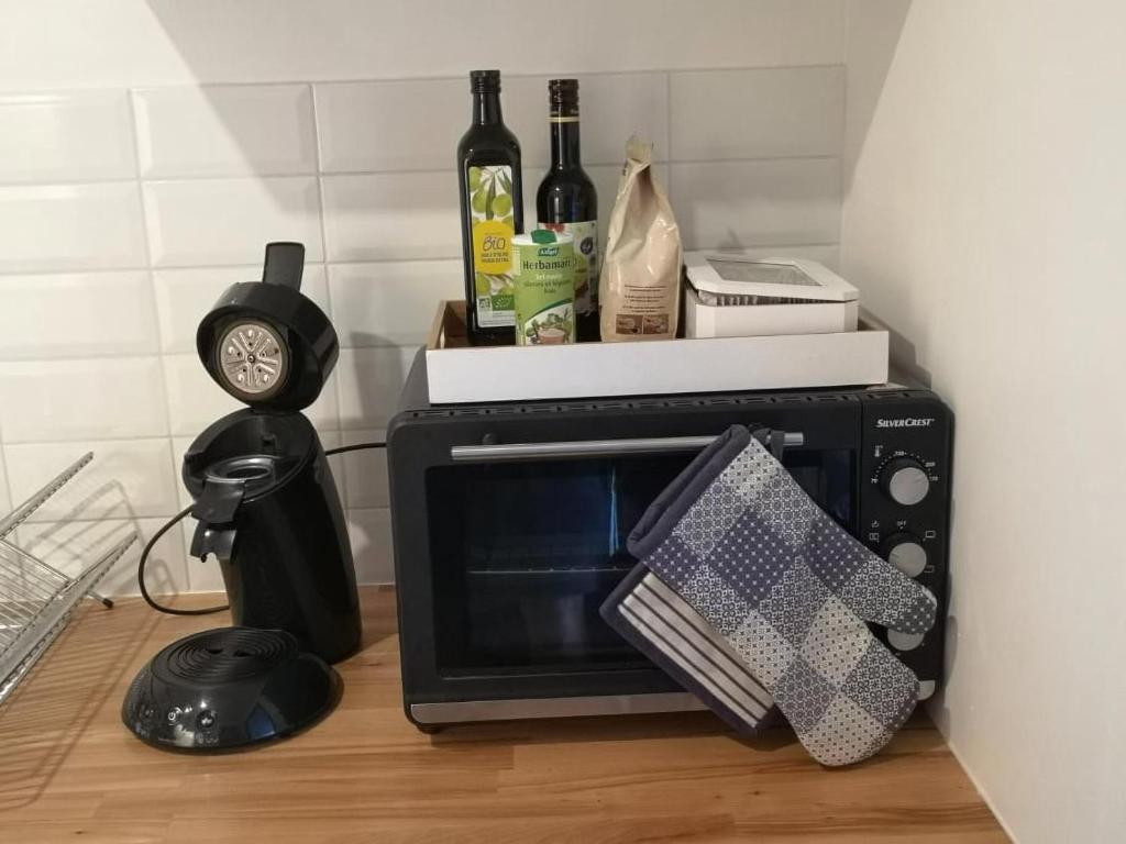 a microwave on a counter with a clock and bottles of wine at Le Petit Pèlerin in Ammerschwihr