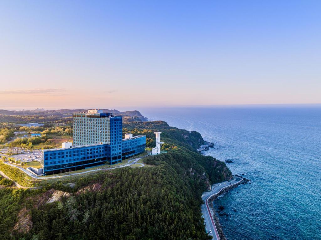 a building on a cliff next to the ocean at Hotel Tops 10 in Gangneung