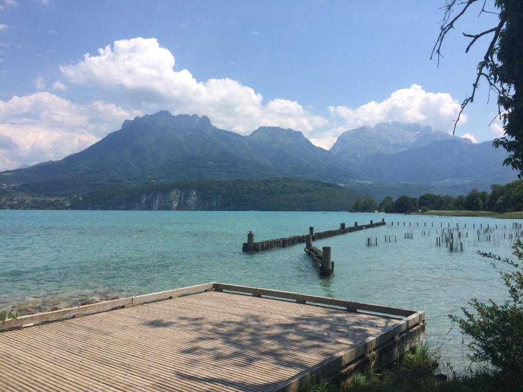 einem See mit einem Dock und Bergen im Hintergrund in der Unterkunft chambre atypique à 200m du lac in Saint-Jorioz