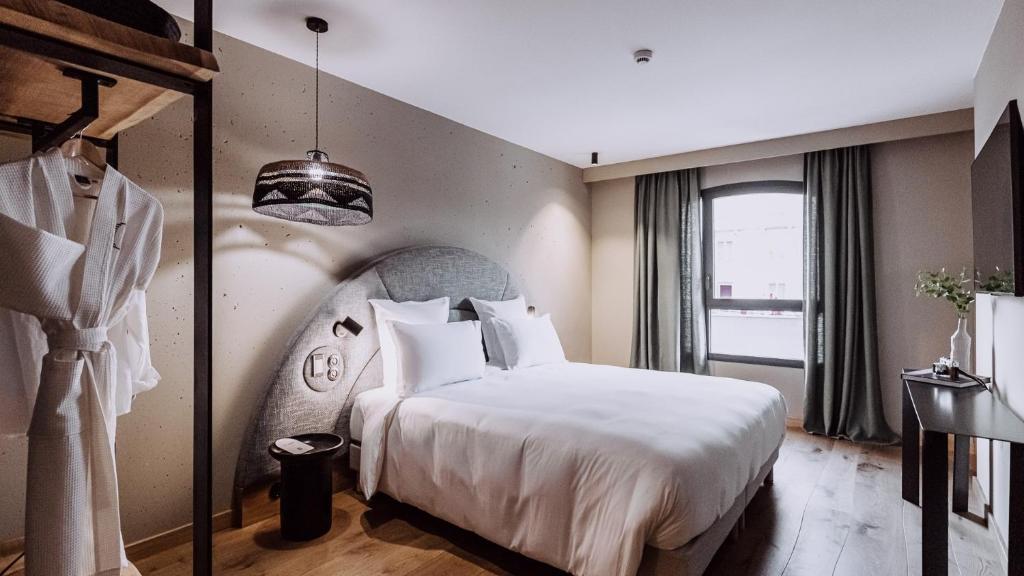 um quarto com uma grande cama branca e uma janela em Le Garage Biarritz Hôtel em Biarritz
