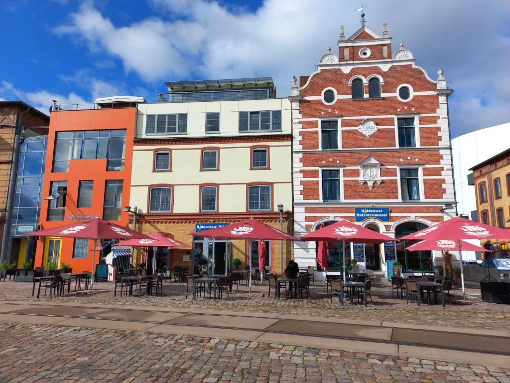 eine Gruppe von Tischen mit Sonnenschirmen vor einem Gebäude in der Unterkunft Hiddenseer Hotel in Stralsund