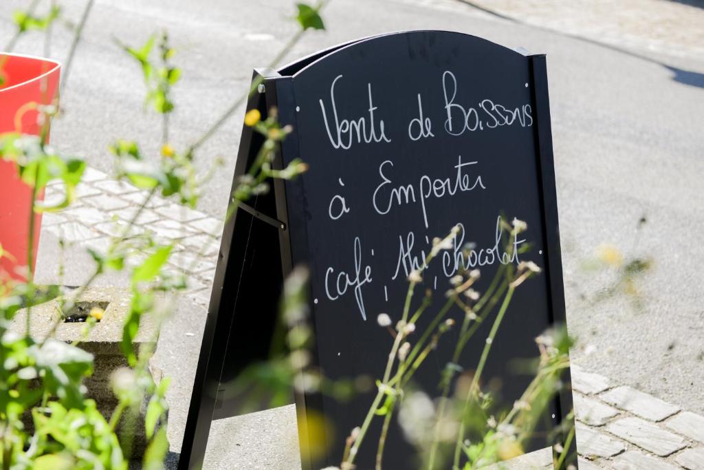 a sign with writing on it next to some plants at Logis Le Saint Hubert in Haybes