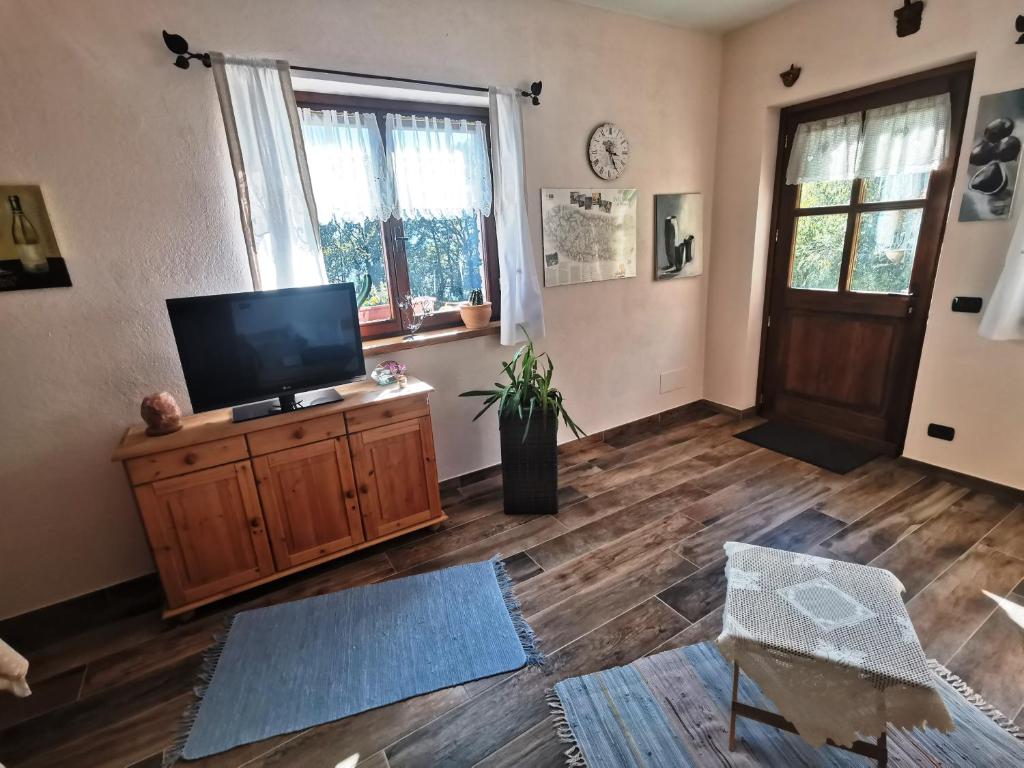 un soggiorno con TV a schermo piatto e pavimento in legno di Casa Bella Vista a Villar San Costanzo