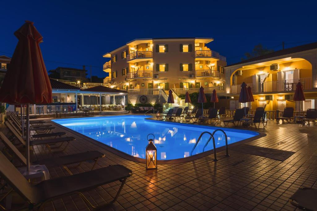 una piscina di fronte a un hotel di notte di Makis studios a Skala di Cefalonia