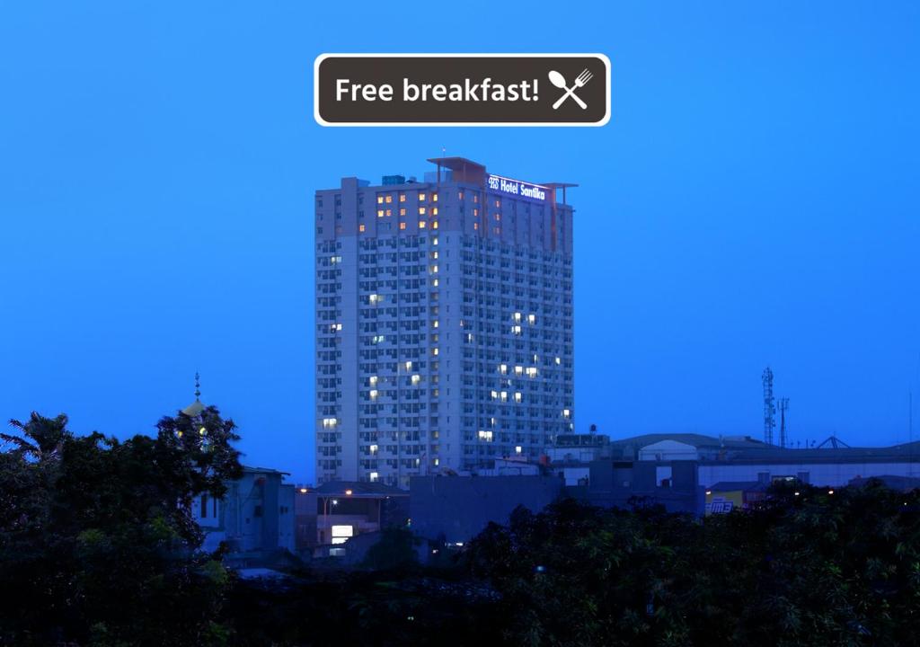 a tall building with a free breakfast sign on it at Hotel Santika Depok in Depok