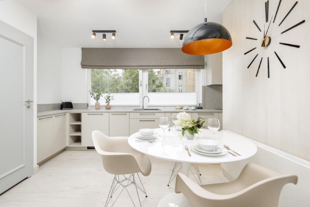 cocina blanca con mesa blanca y sillas en Apartamenty L11, Limanowskiego, en Poznan