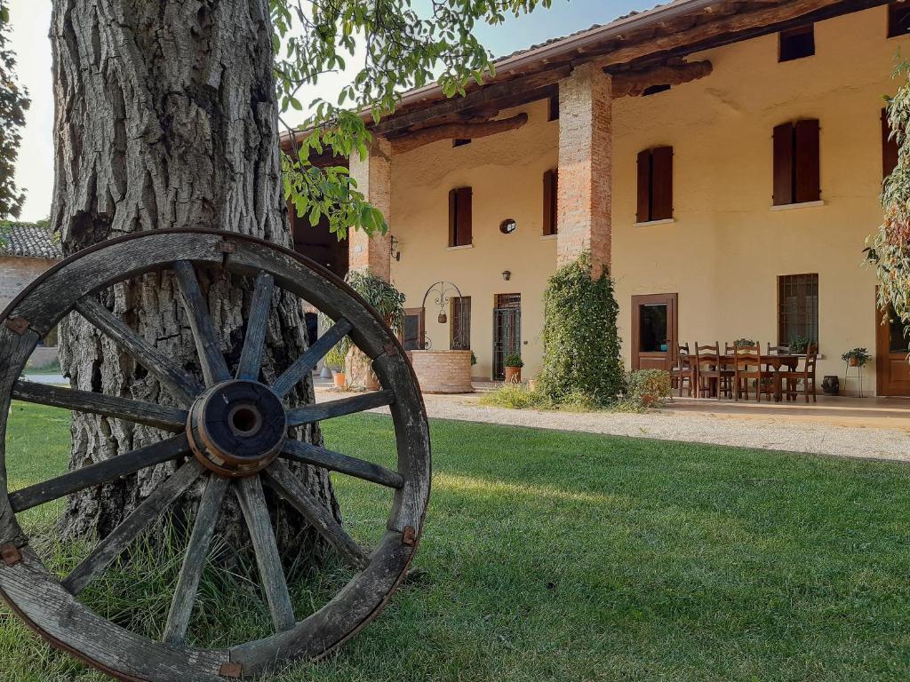 uma roda de vagão de madeira ao lado de uma árvore em B&B Santa Cristina em Montichiari