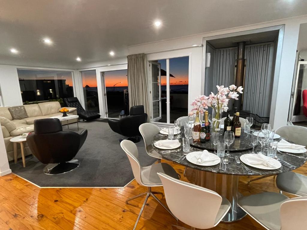 a living room with a table and chairs and a couch at Ocean Front East End Beach House in New Plymouth
