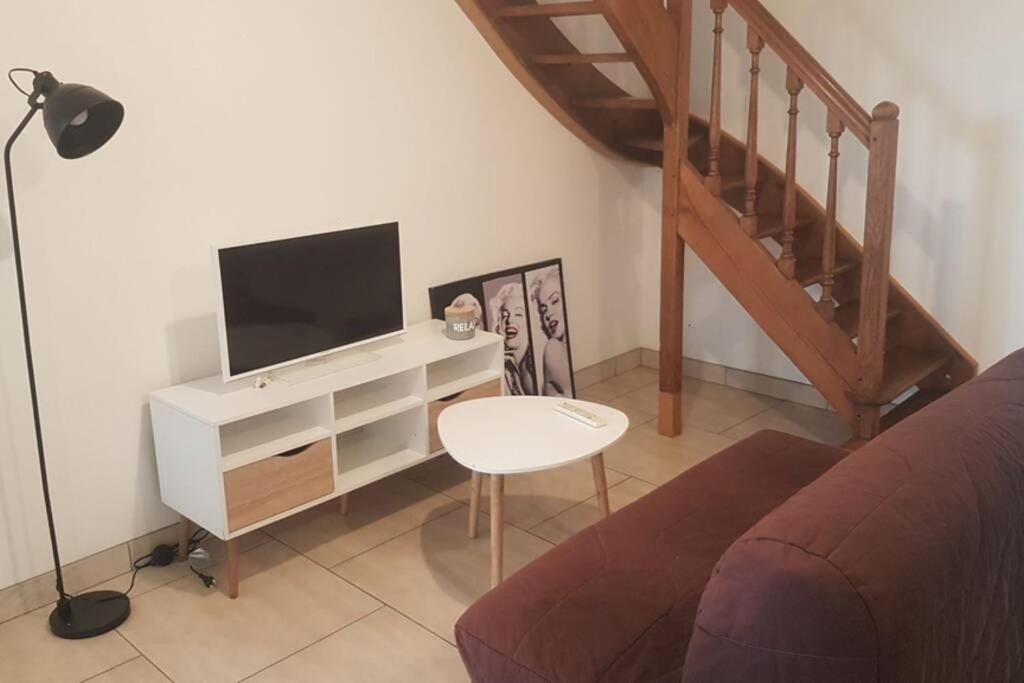 sala de estar con TV y sofá en Maison de bourg avec extérieur., en Grez-en-Bouère