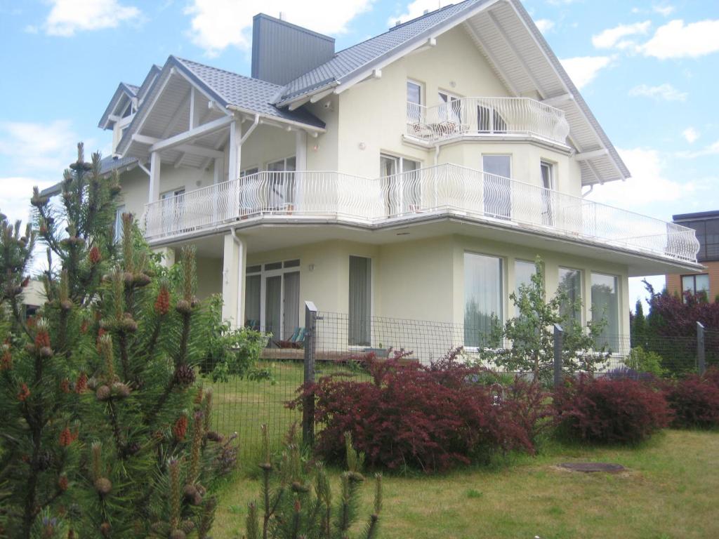 ein weißes Haus mit einer Veranda und einem Hof in der Unterkunft Vila Elvina in Palanga